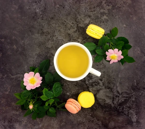 Composición de verano de la taza de té y ramas de escaramujo y flores en la mesa de mármol oscuro, la puesta plana — Foto de Stock