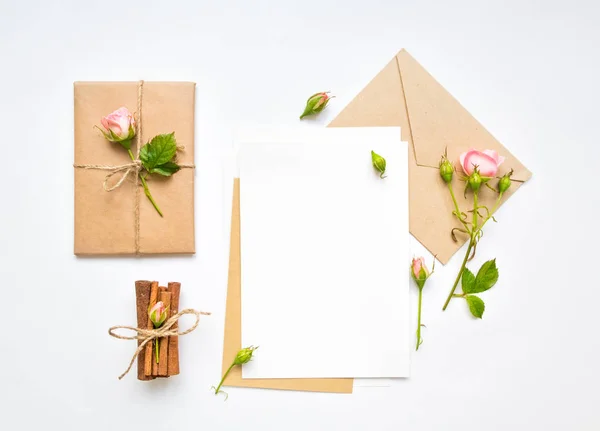 Carta, sobre y regalo sobre fondo blanco. Tarjetas de invitación, o carta de amor con rosas rosadas. Concepto de vacaciones, vista superior, plano —  Fotos de Stock