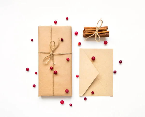 Coffret cadeau et enveloppe en papier éco sur fond blanc. Cadeaux décorés de baies. Concept vacances, vue sur le dessus, plan plat Photo De Stock