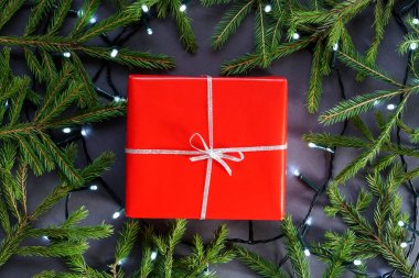 Kırmızı hediye kağıdı, gümüş kurdeleli kutu, çelenk ve köknar ağacı dalları.