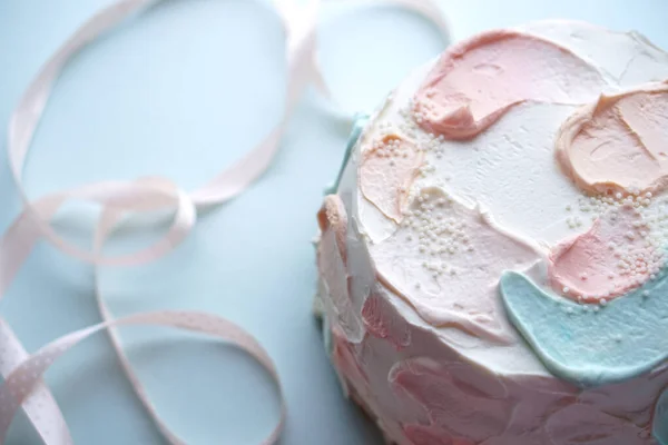 Holiday cake with and pink ribbon on blue blurred background — Stock Photo, Image