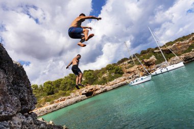 Jumping off cliffs on sunny Cala Sa Nau, Mallorca, Spain clipart