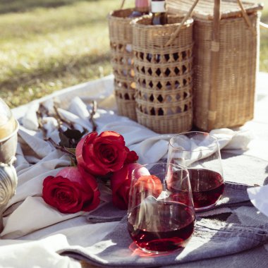Gül ve şarap gün batımında romantik piknik kurmak