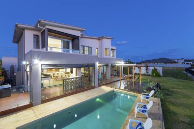 Alacakaranlıkta havuzlu modern çok düzeyli ev dış