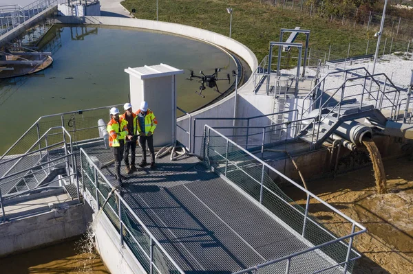 Engineers assesing waste treatment plant with drone — 图库照片
