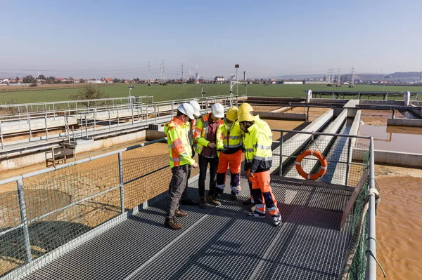 Engineers and workers assesing wastewater plant — 图库照片