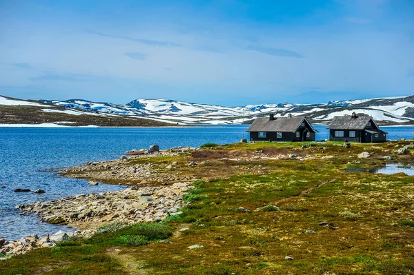 Izolované domy obklopené krásnou krajinou, kopce a hory částečně pokryté bílým sněhem, Norsko — Stock fotografie