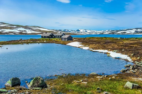 Casas aisladas rodeadas de hermosos paisajes de colinas y montañas parcialmente cubiertas de nieve blanca, Noruega — Foto de Stock