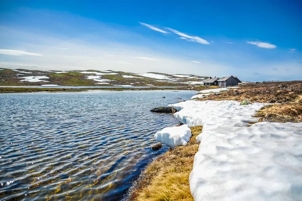 Maisons isolées entourées de magnifiques paysages de collines et de montagnes couvertes partiellement de neige blanche, Norvège — Photo