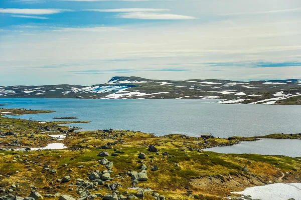 Bela paisagem e paisagem da Noruega, as colinas e montanhas cobertas parcialmente de neve branca e lago azul — Fotografia de Stock