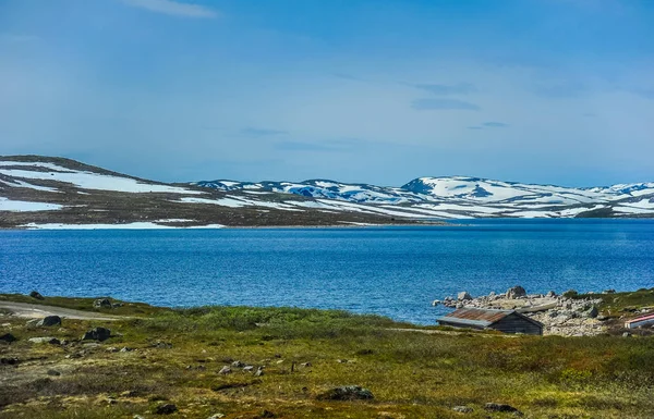 Bellissimo paesaggio e scenario della Norvegia, le colline e le montagne parzialmente coperte di neve bianca e lago blu — Foto Stock