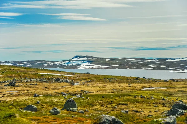 Bela paisagem e paisagem da Noruega, as colinas e montanhas cobertas parcialmente de neve branca e lago azul — Fotografia de Stock