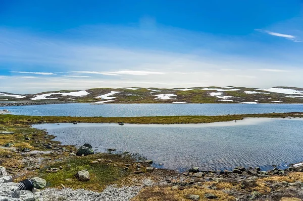 Bellissimo paesaggio e scenario della Norvegia, le colline e le montagne parzialmente coperte di neve bianca e lago blu — Foto Stock