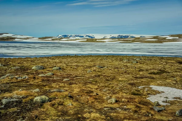 Bela paisagem e paisagem da Noruega, as colinas e montanhas cobertas parcialmente de neve branca e lago azul — Fotografia de Stock