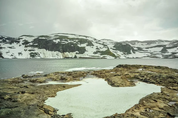 Prachtig landschap en landschap uitzicht van Noorwegen, de heuvels en bergen gedeeltelijk bedekt met witte sneeuw en meer — Stockfoto