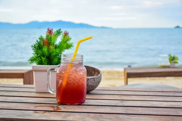 Kühle Getränke servieren ein alkoholfreies Getränk in einer Flasche auf dem Holztisch mit einem verschwommenen Meer im Hintergrund — Stockfoto