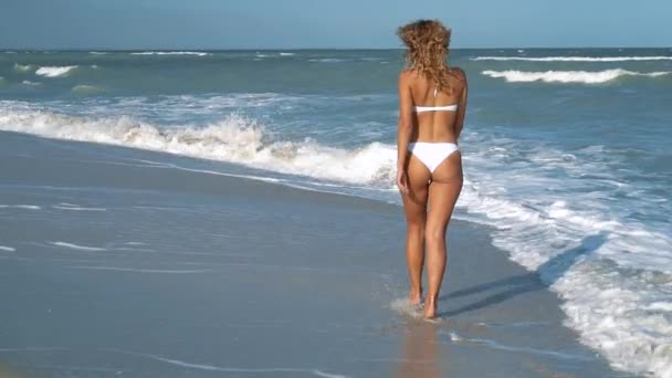 Young beautiful sexy tanned girl in swimsuit runs along the beach. Slow motion. Steadicam. — Stock Video