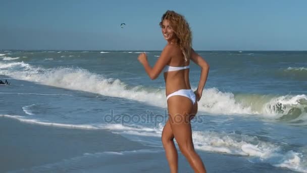 Junge schöne sexy braungebrannte Mädchen im Badeanzug läuft am Strand entlang. Zeitlupe. Schwebestativ. — Stockvideo