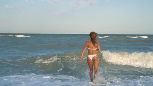 Νέοι όμορφη σέξι μαυρισμένο κορίτσι στο μπανιερό τρέχει κατά μήκος της παραλίας. Αργή κίνηση. Steadicam. — Αρχείο Βίντεο
