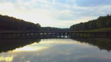 Hava Drone uçuş görüntüleri: Geri uçuş sakin su ve orman günbatımı yumuşak ışık yukarıda. Magestic peyzaj.
