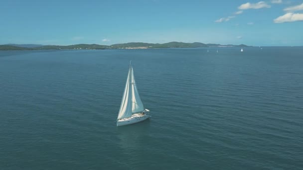 Légi kilátás jacht vitorlázás közelében gyönyörű szigetek. Gyönyörű felhők a háttérben. Luxus jacht a tengerben. — Stock videók