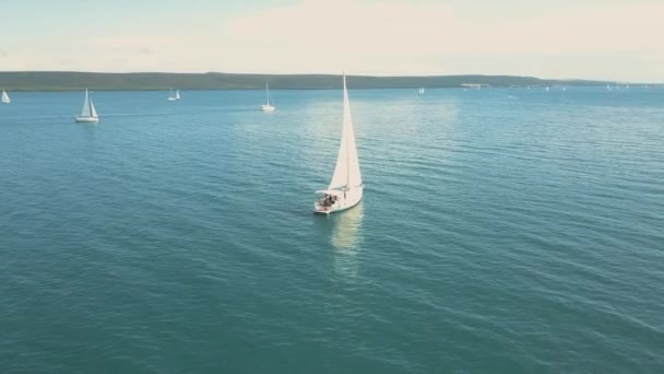 아름다운 섬 근처를 항해하는 요트를 공중에서 볼 수있다. 아름다운 구름 이 배경에 있습니다. 바다에 떠 있는 고급 요트. — 비디오