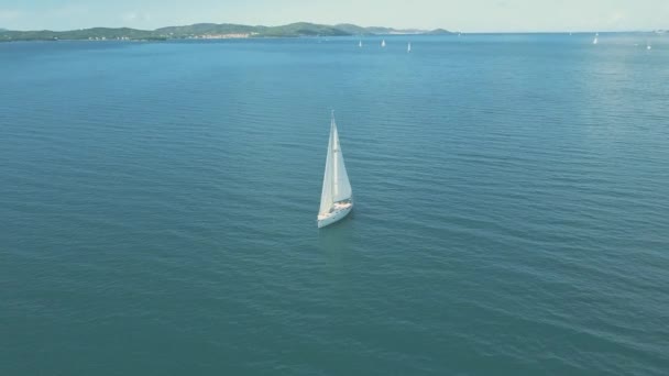 아름다운 섬 근처를 항해하는 요트를 공중에서 볼 수있다. 아름다운 구름 이 배경에 있습니다. 바다에 떠 있는 고급 요트. — 비디오