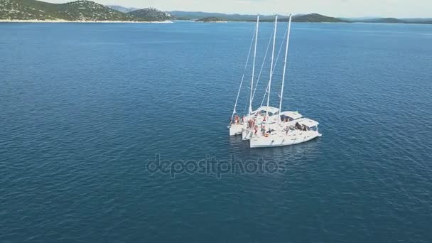 Flygfoto över tre segelbåtar är anslutna, nära vackra öar. Vackra moln i bakgrunden. Lyxbåtar i havet. Människor simma nära yachts — Stockvideo