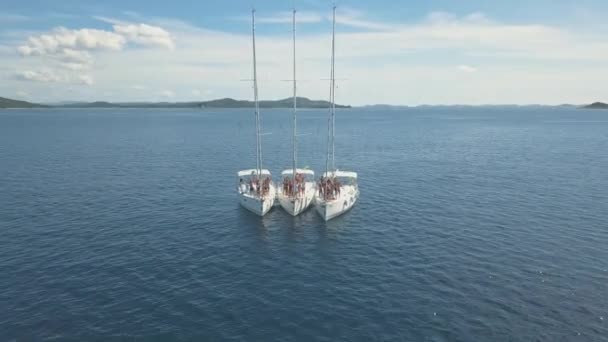 Aerial view of three sailing yachts are connected, near beautiful Islands. Beautiful clouds in the background. Luxury yachts in the sea. People swim near yachts — Stock Video