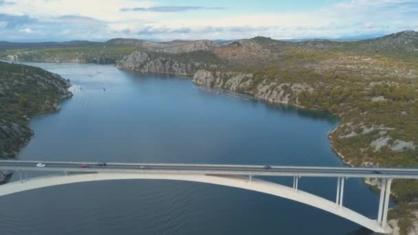 Luchtfoto panoramisch uitzicht met brug en de zee rond de eilanden. Mooi landschap, omgeven met blauwe zee met brug tussen. Autostrada brug met verkeer over de rivier Krka op zonnige dag in Kroatië. — Stockvideo