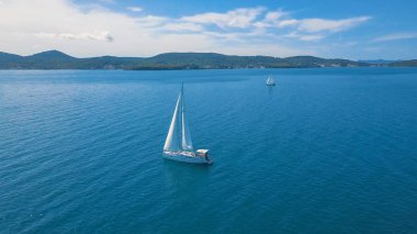 Yat manzaralı, güzel adaların yakınında. Arka planda güzel bulutlar var. Denizde lüks bir yat..