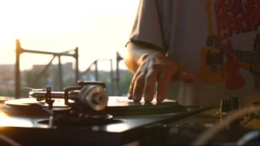 Mix ve sıfırdan, vinil ve karıştırıcı kolları Dj elinde. Ağır çekim 120 fps. Yalpa ile ateş. Günbatımı.