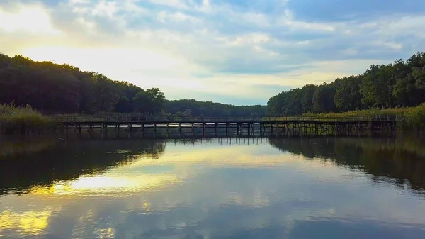 Aerial Drone Flight Filmato: Volo di ritorno sopra calma Acqua e foresta al tramonto luce soffusa. Paesaggio magico . Foto Stock