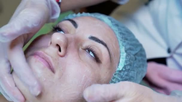 女性美容師は、美容センターで女性のクライアントに化粧品の顔のマスクを作るします。クリーニングの顔 — ストック動画