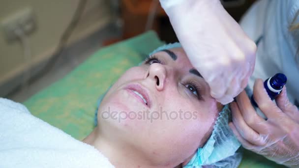 Kosmetikerin fertigt kosmetische Gesichtsmaske für die Kundin im Kosmetikzentrum an. Gesichtsreinigung — Stockvideo