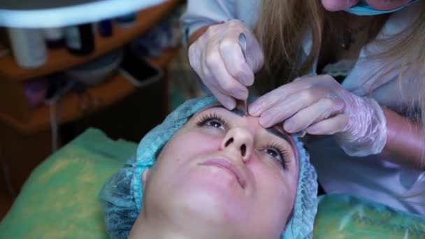 Cosmetologa femminile che fa la maschera facciale cosmetica al cliente femminile al centro di cosmetologia. Pulizia del viso — Video Stock