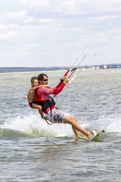Papà e figlio stanno facendo kitesurf sul mare. Il figlio si aggrappa a Papas indietro — Foto Stock