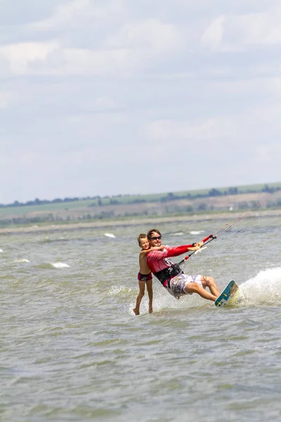 Papá e hijo están haciendo kitesurf en el mar. El hijo se aferra a Papas —  Fotos de Stock