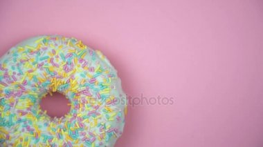 Lezzetli tatlı çörek bir plaka üzerinde döner. Üstten Görünüm. Parlak ve renkli serpilir çörek yakın çekim makro iplik bir pembe vurdu..