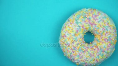 Lezzetli tatlı çörek bir plaka üzerinde döner. Üstten Görünüm. Parlak ve renkli serpilir çörek yakın çekim makro iplik mavi bir arka plan üzerine vurdu..