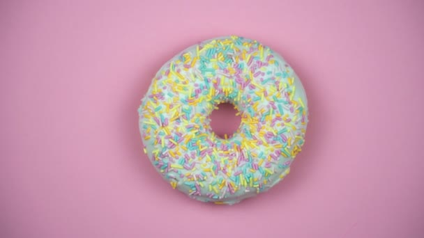 Délicieux donut sucré tournant sur une assiette. Vue de dessus. Lumineux et coloré saupoudré donut gros plan macro tournage sur un fond rose . — Video