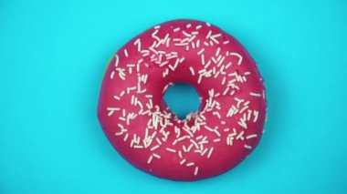 Lezzetli tatlı çörek bir plaka üzerinde döner. Üstten Görünüm. Parlak ve renkli serpilir çörek yakın çekim makro iplik mavi bir arka plan üzerine vurdu..