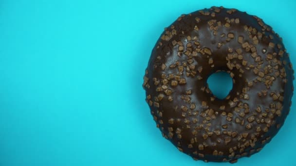 Heerlijke zoete donut draaien op een plaat. Bovenaanzicht. Helder en kleurrijk bestrooid donut close-up macro geschoten spinnen op een blauwe achtergrond. — Stockvideo