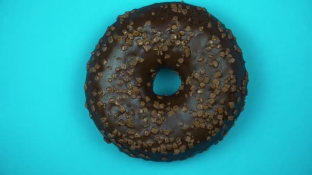 Köstliche süße Donut rotierenden auf einem Teller. Ansicht von oben. hell und bunt bestreut Donut Nahaufnahme Makroaufnahme Drehen auf blauem Hintergrund. — Stockvideo