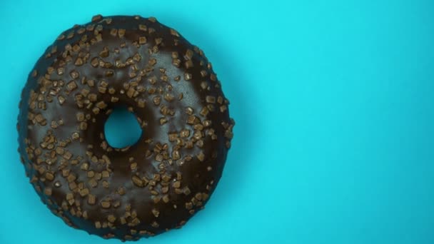 Läckra söta donut roterar på en tallrik. Ovanifrån. Ljusa och färgglada beströdda donut närbild makro skott snurrar på en blå bakgrund. — Stockvideo