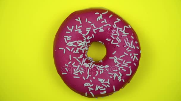 Heerlijke zoete donut draaien op een plaat. Bovenaanzicht. Helder en kleurrijk bestrooid donut close-up macro geschoten spinnen op een gele achtergrond. — Stockvideo