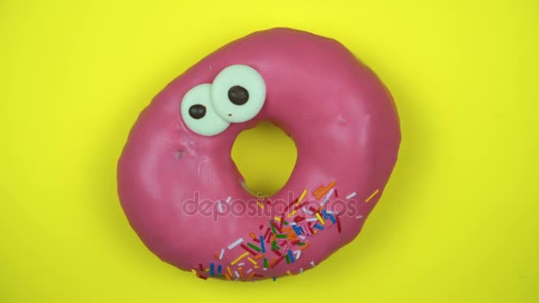 Delicioso donut doce girando em um prato. Vista superior. Brilhante e colorido donut polvilhado close-up macro tiro girando em um fundo amarelo . — Vídeo de Stock