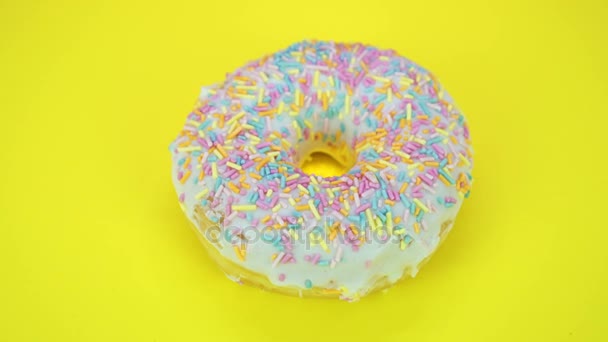 Läckra söta donut roterar på en tallrik. Ovanifrån. Ljusa och färgglada beströdda donut närbild makro skott spinning på gul bakgrund. — Stockvideo