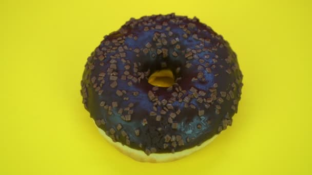 Delicious sweet donut rotating on a plate. Top view. Bright and colorful sprinkled donut close-up macro shot spinning on a yellow background. — Stock Video
