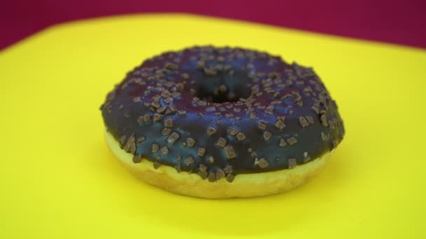 Νόστιμα γλυκά ντόνατ περιστροφή σε ένα πιάτο. Το Top view. Φωτεινό και πολύχρωμο πασπαλισμένες ντόνατ κοντινής πυροβόλησε νηματοποίηση σε κίτρινο φόντο. — Αρχείο Βίντεο